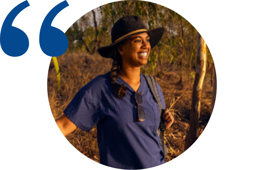 Headshot of a doctor wearing scrubs with a hat on in the bush