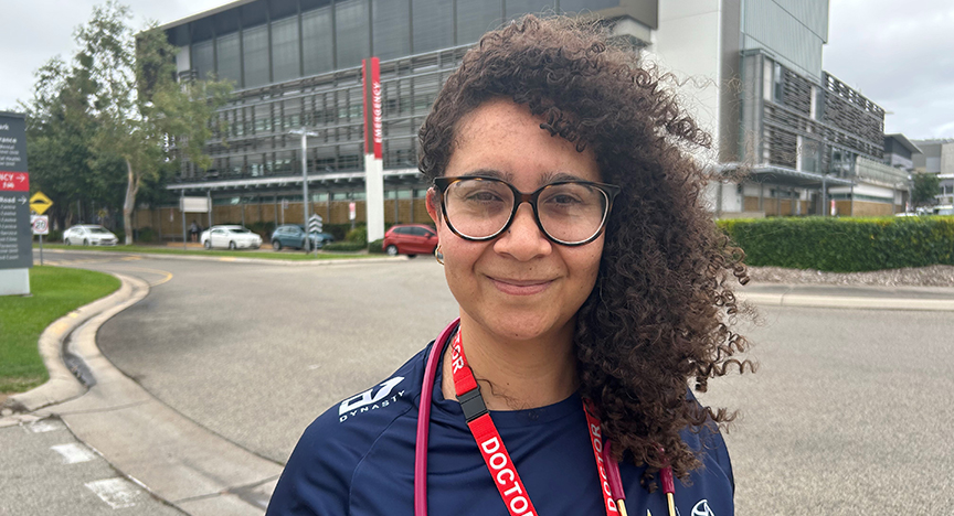 Joanne KACZMAREK with curly hair wearing glasses and a blue shirt.