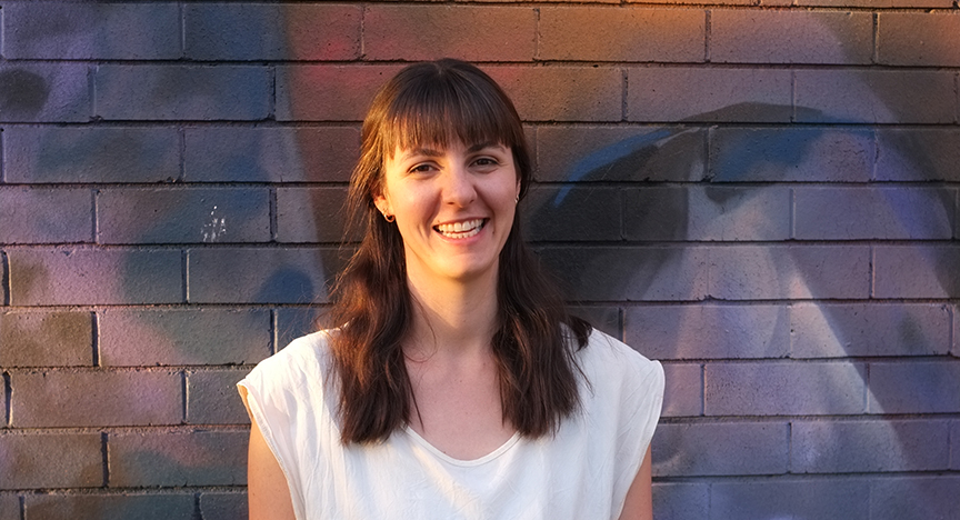 Chantel Van Werkum smiling in front of a brick wall.