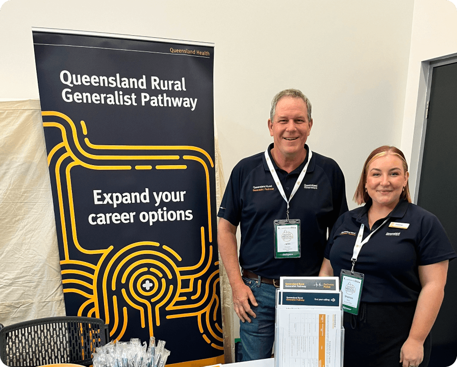 Two rural generalist staff standing next to a pull up banner with the words 'Expand your career options