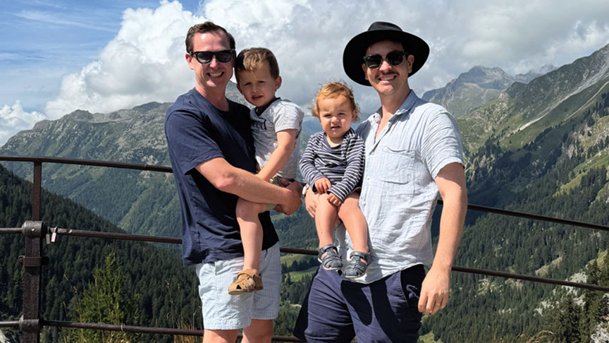 Two men and a child stand together on a mountain, enjoying the scenic view and the beauty of nature around them.